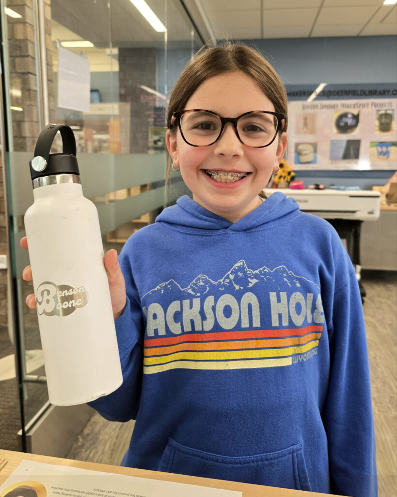 girl in blue hoodie showing off her white engraved water bottle