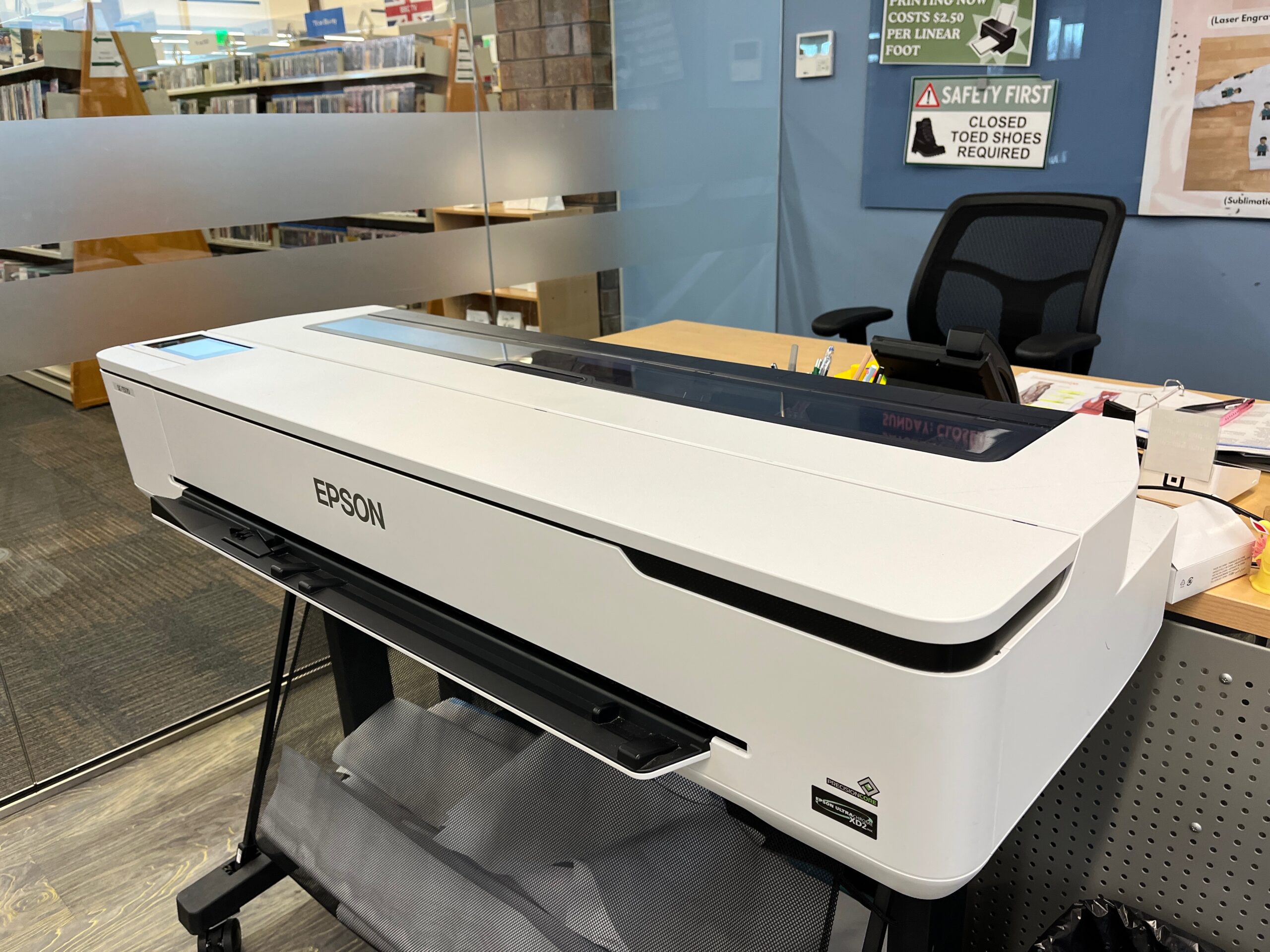 Our grey EPSON large format printer displayed in front of the MakerSpace desk