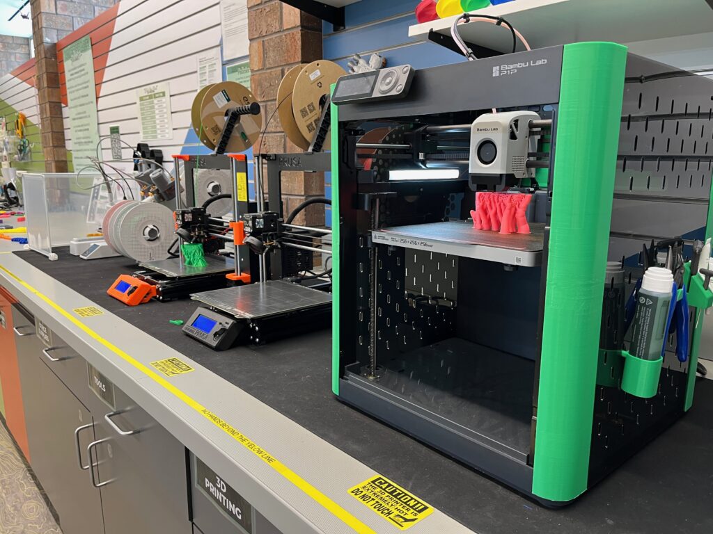 3 3D printers on display all working on a piece of material 