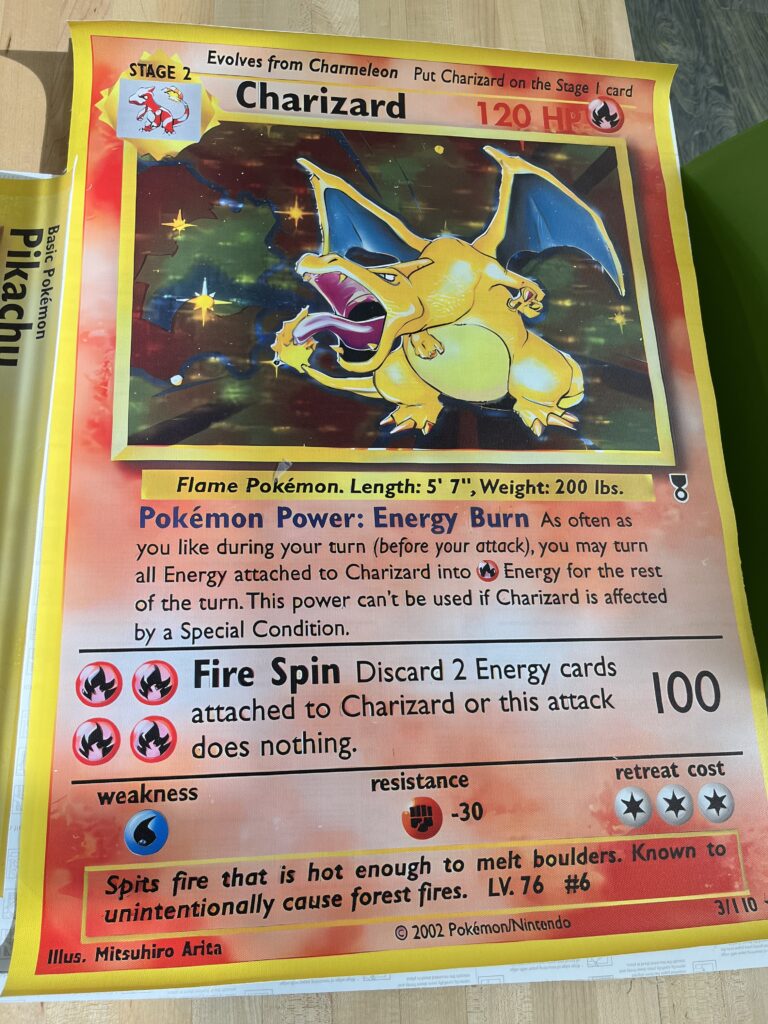 a charizard pokemon card blown up to a poster size and glued onto poster board. 