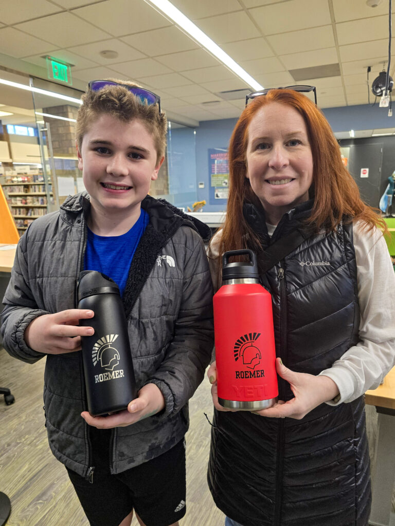 boy holding a black water bottle engraved with DHS Warriors logo, and woman holding red water bottle with the same logo. 